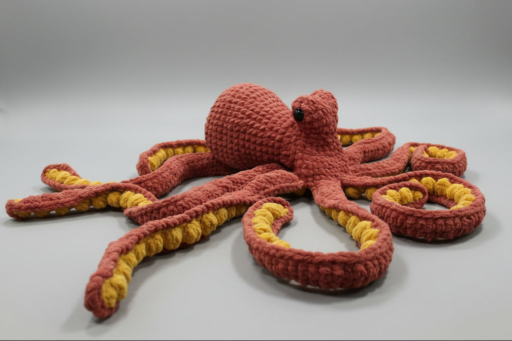 Knitted octopus toy with red and yellow strands on a carpeted floor