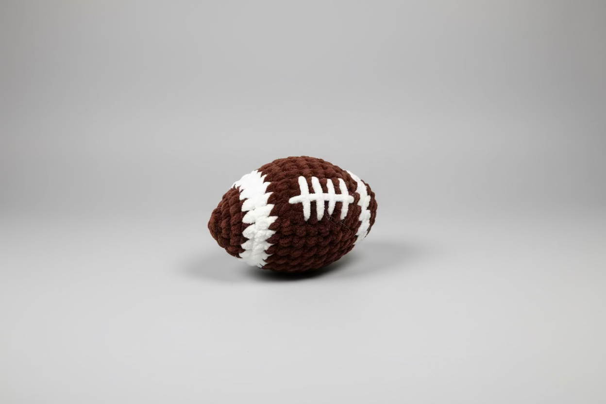 Crocheted football on a wooden surface with a stone wall background